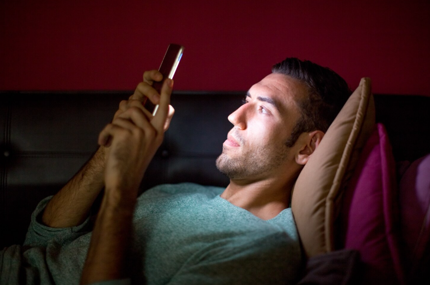 Person searching on phone in bed during late-night life advice searches driven by reflection.