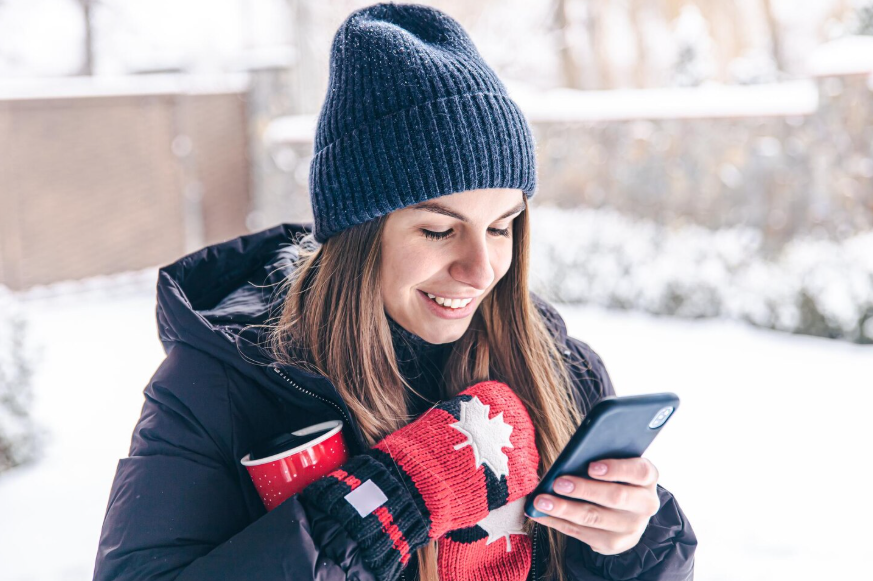 Person using a phone during snowfall reflecting snowstorm search trends.