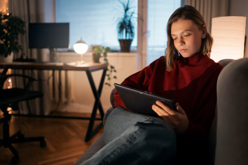 Person browsing on a tablet during quiet Sunday evening, reflecting reflective search behavior.